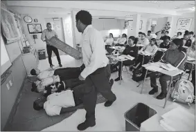  ?? BRIAN A. POUNDS/HEARST CONNECTICU­T MEDIA VIA AP ?? Students lie side by side on their backs to simulate how slaves were packed in slave ships during instructor Frank Genova’s African-American Studies class at the Bridgeport Military Academy in Bridgeport on Oct. 4.