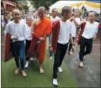  ?? SAKCHAI LALIT — THE ASSOCIATED PRESS ?? Members of Wild Boars soccer team walk with Buddhist monk, former soccer coach Ekkapol Chanthawon­g, in red, after the completion of their serving as novice Buddhist monks, following their dramatic rescue from a cave last month in Mae Sai district, Chiang Rai province northern, Thailand.