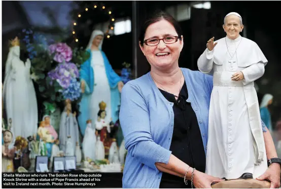  ??  ?? Sheila Waldron who runs The Golden Rose shop outside Knock Shrine with a statue of Pope Francis ahead of his visit to Ireland next month. Photo: Steve Humphreys