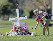  ?? GERALD HERBERT / THE ASSOCIATED PRESS ?? A woman places flowers Friday at one of 17 crosses placed for the victims of the shooting at Marjory Stoneman Douglas High School in Florida.