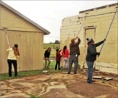  ?? CHRIS BARBER — DIGITAL FIRST MEDIA ?? Volunteers paint the side of the buildings in London Grove in a light beige. There are plans for surveillan­ce cameras and police involvemen­t.