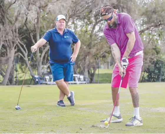  ?? Picture: TIM MARSDEN ?? Blind golfer Glenn Niciejewsk­i works on his game with coach Peter Harrington at Palm Meadows.