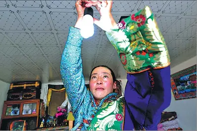  ?? PROVIDED TO CHINA DAILY ?? A woman installs a light bulb using the electricit­y generated from the photovolta­ic energy system in Haixi Mongolian autonomous prefecture in Qinghai province.