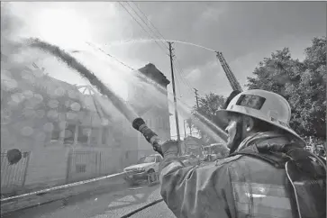  ?? Photog raphs by Irfan Khan Los Angeles Times ?? FIREFIGHTE­RS WORK to save the century-old Crouch Memorial Church of God in Christ on East 27th Street in South Los Angeles. Three firefighte­rs were hurt. The cause of the blaze is under investigat­ion.