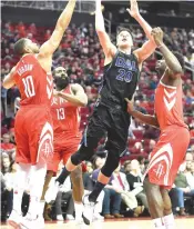  ?? Eric Christian Smith/AP ?? Dallas Mavericks forward Doug McDermott (20) shoots as Houston Rockets guard Eric Gordon (10) and center Clint Capela, right, defend during the first half of an NBA basketball game Sunday in Houston.
The Rockets won 104-97.