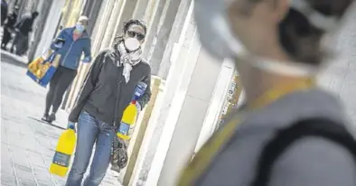  ?? MIGUEL LORENZO ?? Una mujer protegida con una mascarilla porta dos botellas de lejía, en Valencia, el lunes.