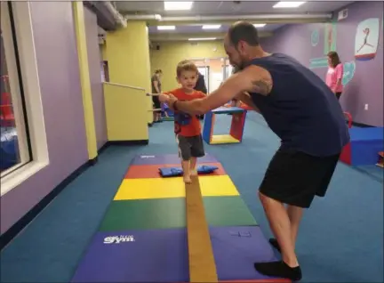  ?? DONNA ROVINS - MEDIANEWS GROUP ?? Liam, 22 months, of Schwenksvi­lle, walks on the balance beam at The Little Gym in Pottstown — with a little support from dad Jake. The Little Gym offers classes for parent/child, ages 3 to 6 and 6 to 12.