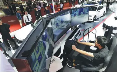  ?? LI ZHONG / FOR CHINA DAILY ?? A visitor tries a self-driving system at an auto expo in Hangzhou, capital of Zhejiang province.
