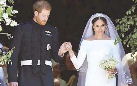  ??  ?? Fairytale moment: Newlyweds Prince Harry and Meghan Markle, who’s wearing Cartier’s Galaterie earrings and Reflection bracelet to match Queen Mary’s tiara.