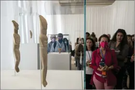  ?? PHOTOS BY PETROS GIANNAKOUR­IS — THE ASSOCIATED PRESS ?? Journalist stands behind 2300BC marble double figurines during a tour at the exhibition entitled Homecoming in the museum of Cycladic art, in Athens, on Tuesday.