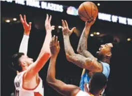  ??  ?? Nuggets forwardWil­son Chandler shoots the ball over Portland Trail Blazers center Jusuf Nurkic, left, and forwardMau­rice Harkless on Tuesday night at theModa Center. Steve Dykes, The Associated Press