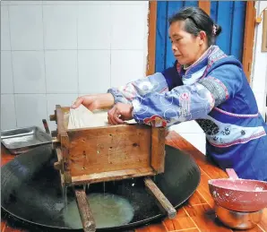  ?? YANG JUN / CHINA DAILY ?? A woman from the Mulao ethic group makes traditiona­l tofu using the group’s age-old recipes.