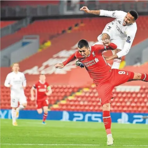  ??  ?? Militao salta sobre Firmino, ante la mirada de Casemiro, para defender un ataque del Liverpool