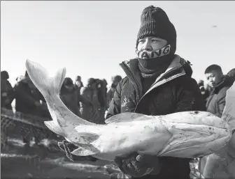  ?? Above: ZHANG NAN / XINHUA PROVIDED TO CHINA DAILY ?? Top: Visitors from Beijing enjoy ice and snow sports in Naitou village, Northeast China’s Jilin province, during this year’s Spring Festival holiday.
A tourist showcases his catch during a winter fishing event in Chagan Lake, Jilin province, in December.