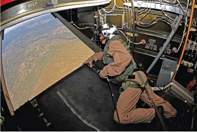  ??  ?? Right: An MV-22B crewman peers out the cargo ramp as the world flashes by below. It is imperative that crewmen use harnesses, since the Osprey is basically powered by the same engines as the KC-130J Hercules. All that power results in tremendous accelerati­on coupled with a superb climb rate, so crew members need to hang on for the ride.