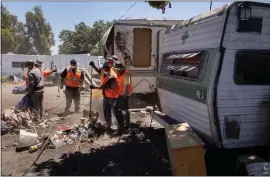  ?? FILE: DAI SUGANO — STAFF PHOTOGRAPH­ER ?? Cleanup crews for the city of San Jose remove items and trash from outside of some tents and RVs in the homeless encampment located along Coleman Avenue in San Jose on June 28, 2021.