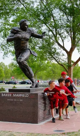  ?? Brian Bahr, Getty Images ?? Young fans show off their Heisman Trophy pose in front of the newly unveiled statue of quarterbac­k Baker Mayfield of the Oklahoma Sooners after the spring football game outside Gaylord Family Oklahoma Memorial Stadium on Saturday in Norman, Okla.