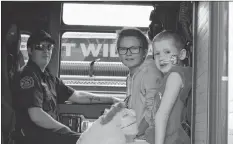  ??  ?? 2017 wish kid Karissa Bezanson (left) and 2018 wish kid Sorren Spinney (right) sit in a Berwick firetruck while attending the 10th annual charity softball tournament in Waterville.