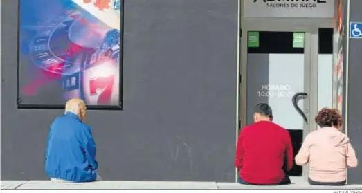  ?? JAVIER ALBIÑANA ?? Tres personas esperan en la puerta de una casa de apuestas en Málaga.