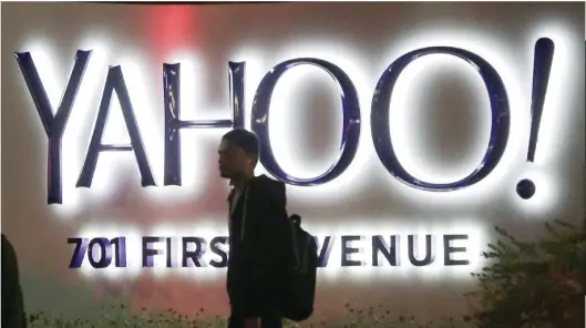  ?? — Reuters ?? A man walks past the Yahoo logo in front of its headquarte­rs in Sunnyvale, California.