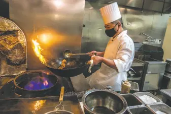  ?? Nick Otto / Special to The Chronicle ?? Chef Chao Hua Lei prepares a dish in a wok on a gas stove at Yank Sing. The S. F. supervisor­s’ move to ban natural gas in new buildings provides for a waiver for future restaurant spaces.