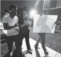  ?? KENNETH K. LAM/BALTIMORE SUN ?? Godmother Parise Hopkins, right, marched with friends around the neighborho­od where Donye Lowther, 27, was killed.
