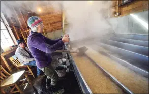  ?? Kristopher Radder / Associated Press ?? In this March 5, 2020, file photo, Beverly Thurber, of Lilac Ridge Farm, in Brattlebor­o, Vt., checks the density of the sap that is being boiled for maple syrup. The coronaviru­s pandemic forced some states to cancel their annual maple season celebratio­ns in 2020, but some New England producers with safety precaution­s in place are welcoming back the public in 2021.