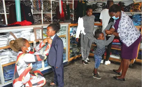  ?? — Picture: Tinai Nyadzayo ?? Mrs Roseline Mupangano (left) assists her daughter Alliswell Mupangano, a Grade One pupil at Rock of Ages Academy, to try on her school uniform at a Mutare shop in preparatio­n for the opening of schools next week.