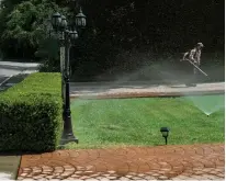  ?? Tribune News Service/los Angeles Times ?? A gardener uses a leaf blower while cleaning a driveway as sprinklers water the front lawn of a home on Sunset Boulevard near Carmelina Avenue in Los Angeles.