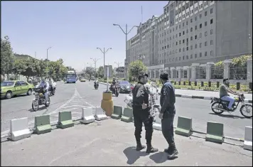  ?? VAHID SALEMI / ASSOCIATED PRESS ?? Police officers stand guard as vehicles drive past Iran’s parliament building in Tehran on Thursday. Police increased their patrols in the streets and subway stations Thursday, a day after a pair of Islamic State-claimed attacks on Iran’s parliament...