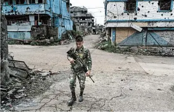  ?? HANNAH REYES MORALES/FOR THE WASHINGTON POST ?? A soldier patrols empty streets Nov. 15, 2017, in Marawi, Philippine­s. Marawi was left in ruins after Islamic State-inspired militants laid siege to the city in a battle that lasted months.