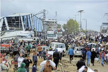  ?? /Reuters ?? Subsistenc­e: Palestinia­ns carry bags of flour they grabbed from an aid truck near an Israeli checkpoint in Gaza City at the weekend as residents face a hunger crisis.