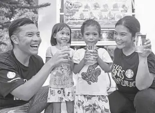  ?? ?? CHILDREN-BENEFICIAR­IES are all smiles while handling their glasses of clean, safe drinking water from the third aquatower in the country built by Starbucks Philippine­s, The Starbucks Foundation, and Planet Water Foundation at Talao-talao Elementary School in Lucena, Quezon. Joining them are volunteer Starbucks partner-employees.