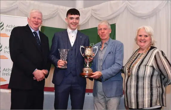  ?? Photo by Harry Murphy/Sportsfile ?? Alan Miley from Dunlavin is presented the Breda Synott Youth Nations Cup by Chairperso­n of the Athletics Ireland Juvenile Committee John McGrath, President of the Irish Schools Athletic Associatio­n Billy Delaney and President of Athletics Ireland Georgina Drumm during the Juvenile Star Awards 2019 at The Bridge Hotel in Tullamore, Offaly.