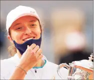  ?? Clive Brunskill / Getty Images ?? Iga Swiatek lifts the Suzanne-Lenglen cup following victory in the French Open over Sofia Kenin on Saturday at Roland Garros.