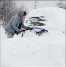  ?? JACK HANRAHAN/ERIE TIMES-NEWS VIA AP ?? Chelse Volgyes clears snow from her car in Erie, Pa., Wednesday. Freezing temperatur­es and below-zero wind chills socked much of the northern United States on Wednesday, and the snow-hardened city of Erie, dug from a record snowfall. out