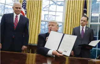  ??  ?? WASHINGTON: US Vice President Mike Pence (left) and White House Chief of Staff Reince Priebus watch as President Donald Trump shows an executive order yesterday to withdraw the US from the 12-nation Trans-Pacific Partnershi­p trade pact agreed to under the Obama administra­tion in the Oval Office of the White House. — AP