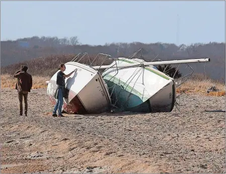  ?? SARAH GORDON/THE DAY ?? Brothers Jacob, left, and Filip Aubrecht of Mystic check out two abandoned sailboats Tuesday on a beach at Bluff Point State Park in Groton.