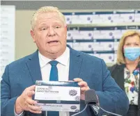  ?? FRANK GUNN THE CANADIAN PRESS ?? Premier Doug Ford holds up a rapid test kit during his daily briefing on Nov. 24. Since the announceme­nt of the approval of the vaccine, however, the province seems to have lost interest. Ford hasn’t faced the press since Monday, Bruce Arthur writes.