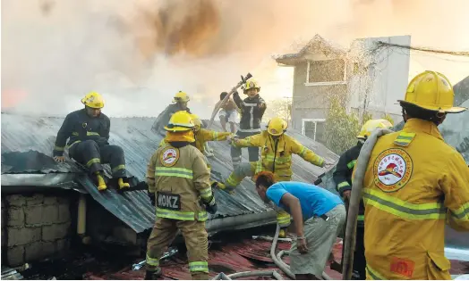  ?? (SUN.STAR FOTO/ARNI ACLAO) ?? EMERGENCY. Firefighte­rs find a vantage point from where to attack the fire in Duljo, Fatima yesterday.