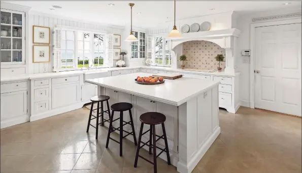  ?? AFA Homes / William Raveis Real Estate / Contribute­d photos ?? Views of the water can be enjoyed from the open kitchen boasting an island with breakfast bar, white cabinetry and a dining area with built- ins and window seat overlookin­g the water.