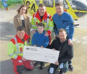 ??  ?? Sara, Steven, back right, and six-year-old Leon Edwards hand over the cheque to the air ambulance crew.