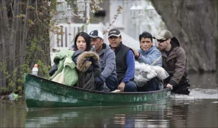  ?? GRAHAM HUGHES, THE CANADIAN PRESS ?? Members of a family are helped with some belongings after their home had to be evacuated Sunday in the Montreal borough of Pierrefond­s.