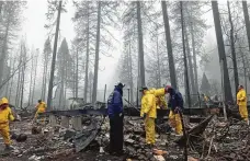  ?? Kathleen Ronayne / Associated Press ?? After a brief delay to let a downpour pass, volunteers resume their search for human remains at a mobile home park in Paradise, Calif., on Friday. At least 84 people have died in the fire.