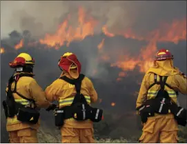  ?? PALMOUR IV/SAN DIEGO UNION-TRIBUNE VIA AP ?? Upland firefighte­rs (from left), Nima Homayounie­h, Joseph Armendariz, and Capt. Joe Burna, watch as flames burn toward Highway 94 near Potrero on Monday. HAYNE