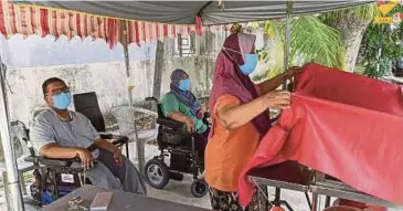  ?? ZUHAINY ZULKIFFLI PIC BY ?? Sarifah Bee Abdul Jabar helping her children, Mohd Yassin Mohd Packer and Norfarhana Mohd Packer, open their fruit stall at Bukit Dumbar in George Town.