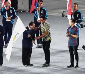  ??  ?? Grand finale: Fireworks light up the National Stadium in Bukit Jalil as Barredo (above) receives the Games flag from Khairy while SM Nasarudin (right) looks on during the closing ceremony.