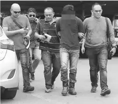  ??  ?? A CID team leads the suspect (second right) to the Miri Central police station.