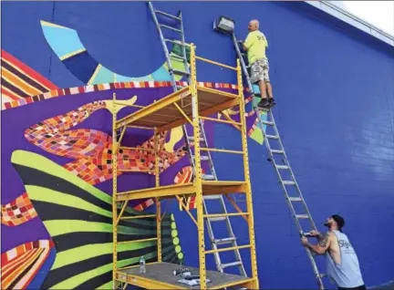  ?? BEN LAMBERT - THE REGISTER CITIZEN ?? A mural by Danielle Mailer is being installed on the rear wall of Staples in Torrington, overlookin­g the Naugatuck River.