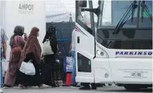  ?? CP ?? Refugees from Afghanista­n and Canadian citizens board a bus after being processed at Pearson Airport in Toronto. They are arriving indirectly from Afghanista­n in a first round of evacuation­s.